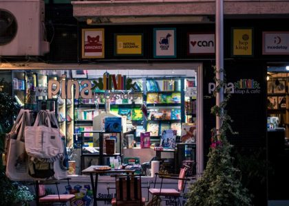 Charming nighttime bookstore and cafe scene, inviting ambiance with outdoor seating and books on display.